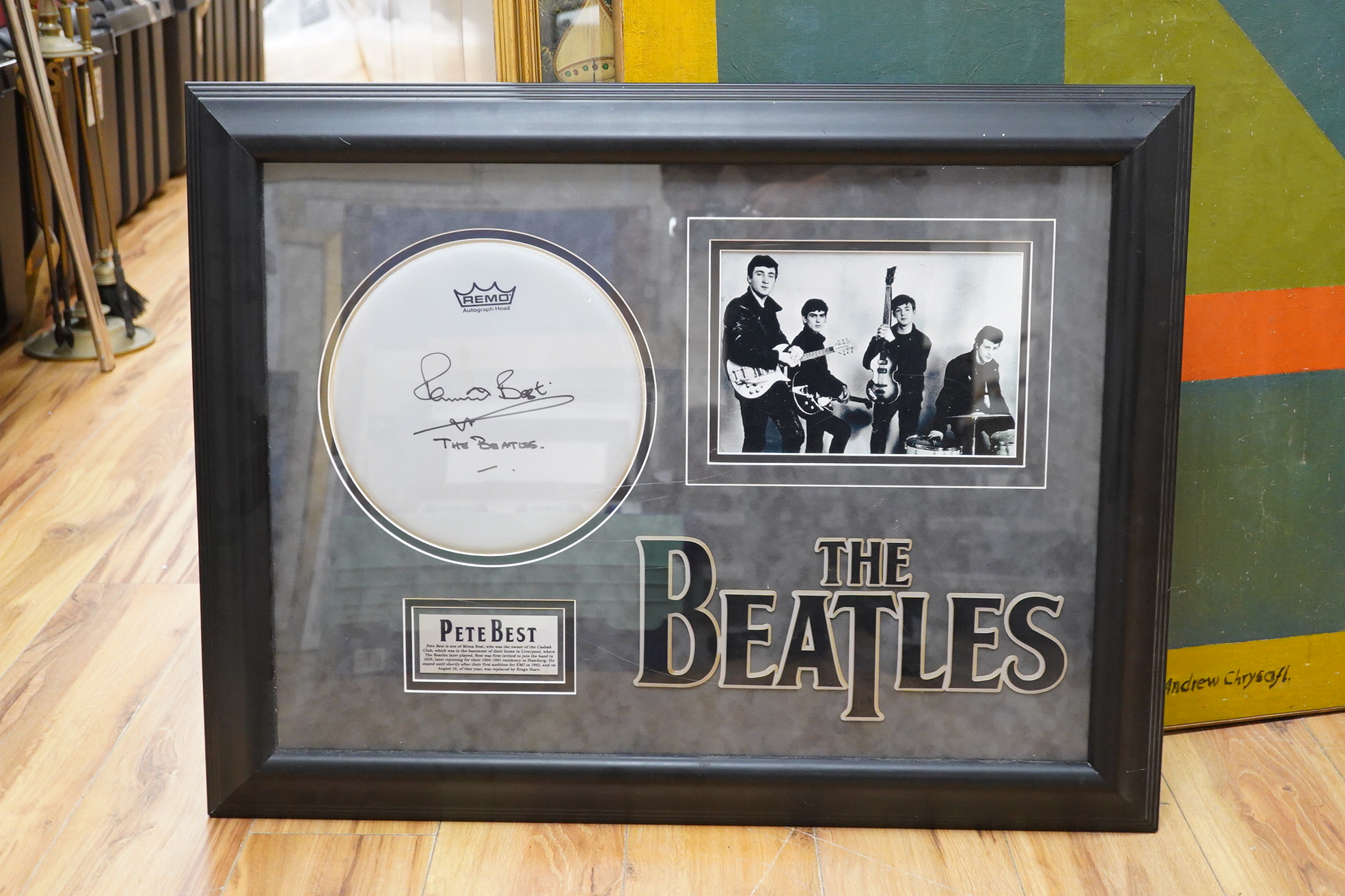 A mounted and framed Remo drum skin, signed by Pete Best, framed alongside a photograph of The Beatles including Best, with title and information panel below, oval dimensions of frame 62 x 81cm